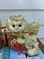 Detail view of pale yellow, coral and gold floral ceramic foo dog pair