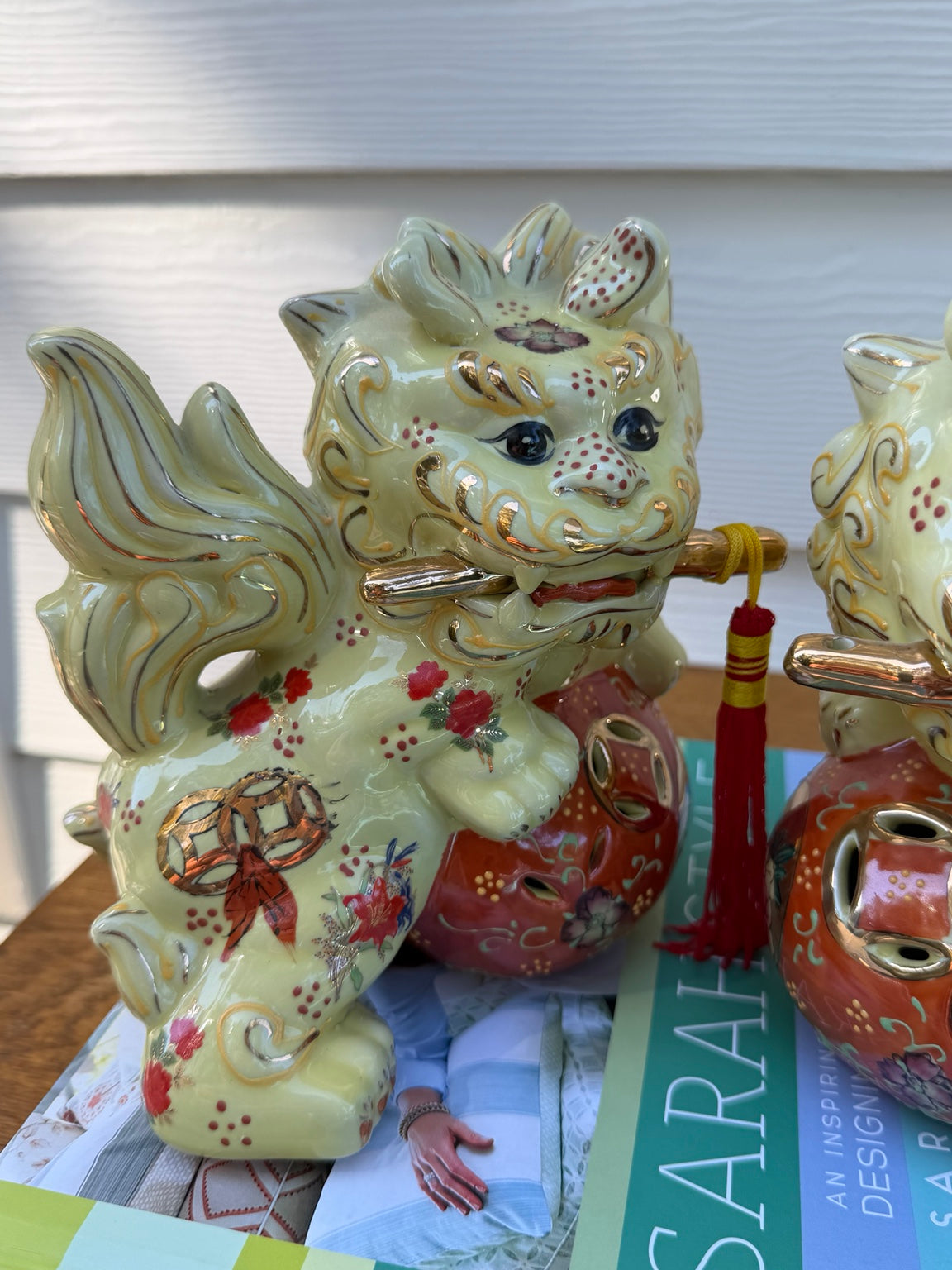 Detail view of pale yellow, coral and gold floral ceramic foo dog pair