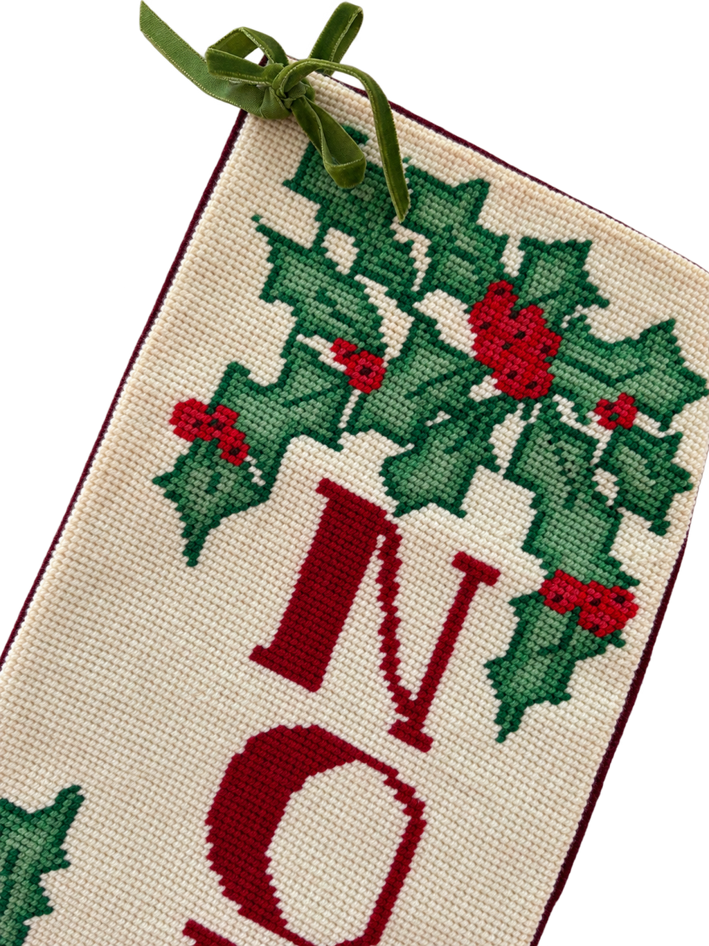 Portrait close-up of holly needlepoint, NOEL lettering and green ribbon bow