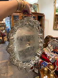 Ornate silver-tone oval serving tray with decorative handles and engraved scrollwork
