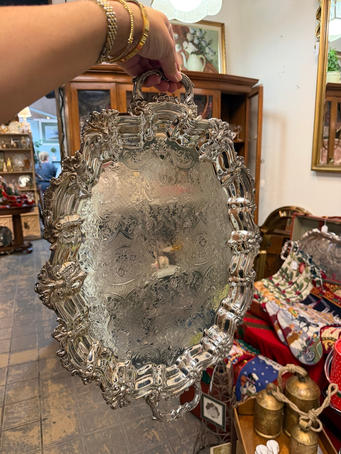 Ornate silver-tone oval serving tray with decorative handles and engraved scrollwork