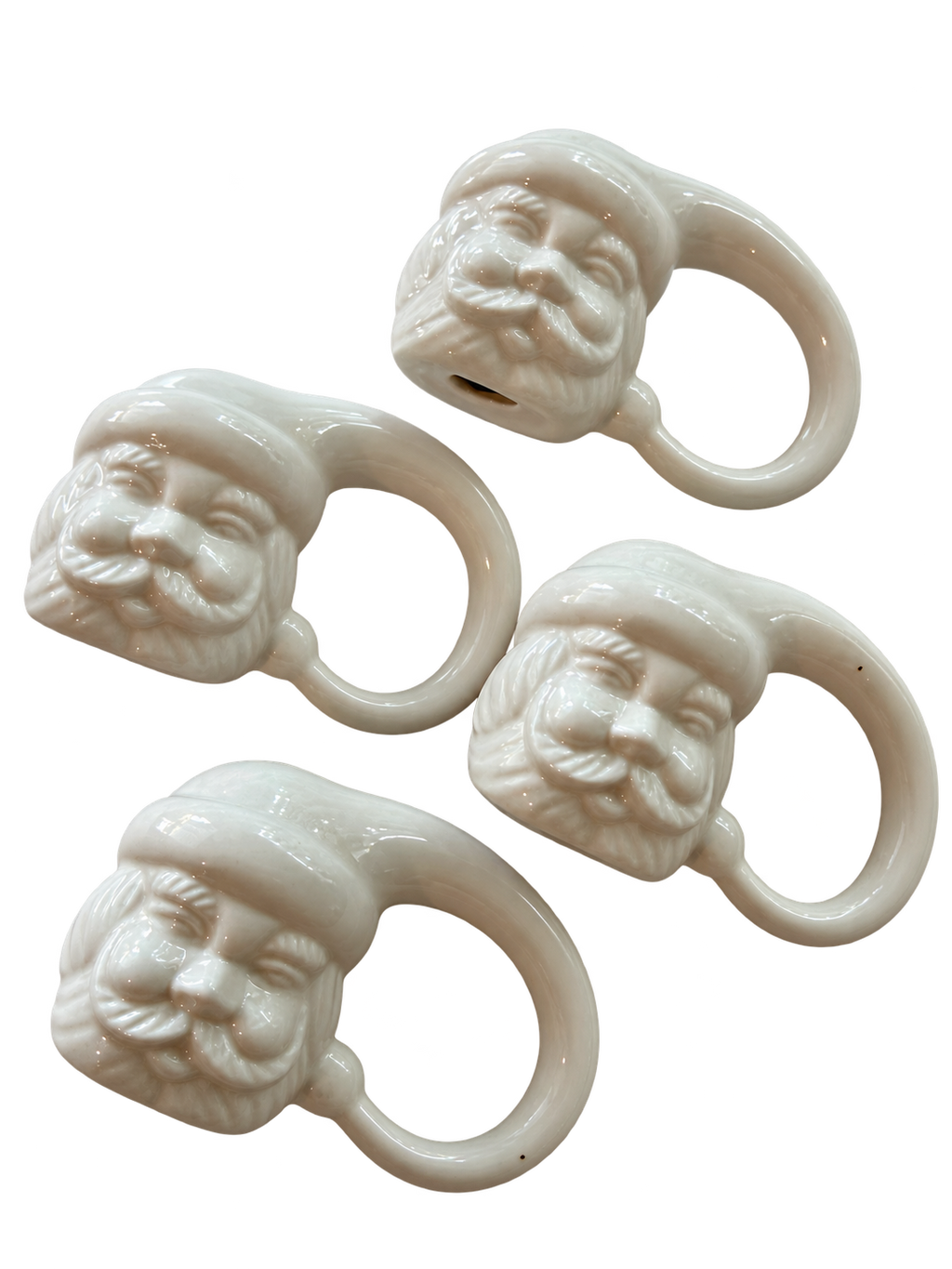 Angled view of four white glazed ceramic Santa napkin rings